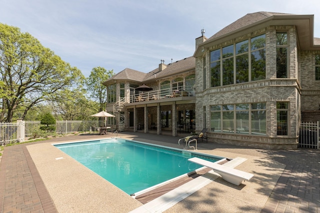 view of swimming pool featuring a patio area and a diving board