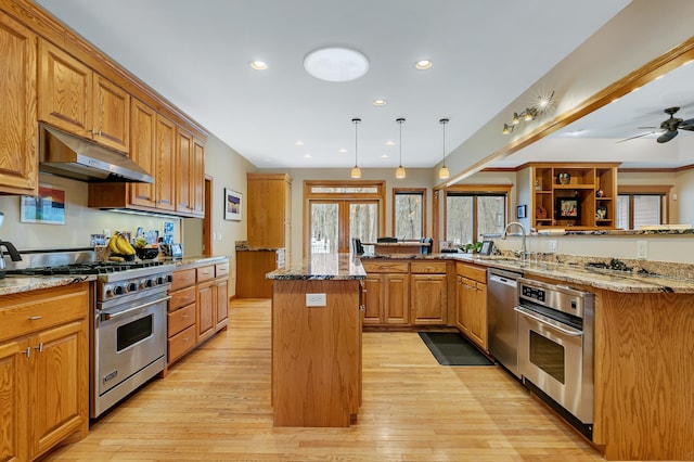 kitchen featuring a center island, light hardwood / wood-style flooring, light stone counters, stainless steel appliances, and ceiling fan