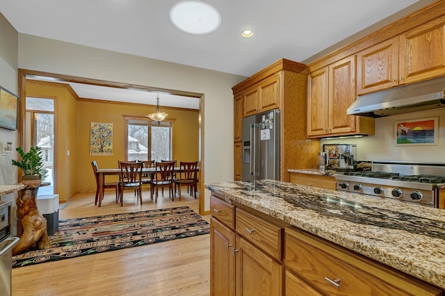 kitchen with high end refrigerator, light stone counters, range, and light hardwood / wood-style flooring