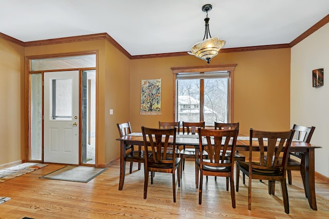 dining area featuring light wood-type flooring and crown molding