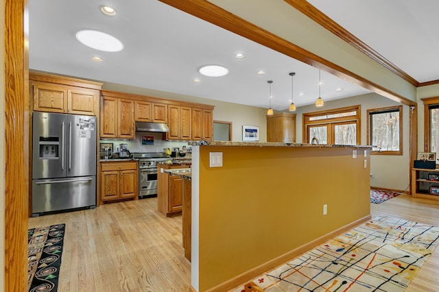 kitchen with appliances with stainless steel finishes, a kitchen island, hanging light fixtures, and light hardwood / wood-style floors