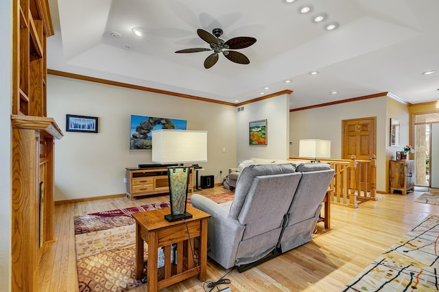 living room featuring a raised ceiling, ceiling fan, and light hardwood / wood-style floors