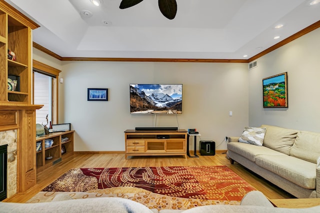 living room featuring a tray ceiling, light wood-type flooring, and ceiling fan