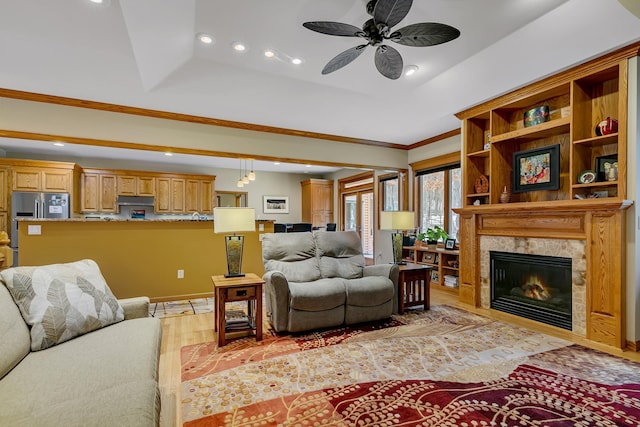 living room featuring light wood-type flooring, a tray ceiling, ceiling fan, and ornamental molding