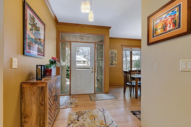 foyer entrance with light hardwood / wood-style floors and crown molding