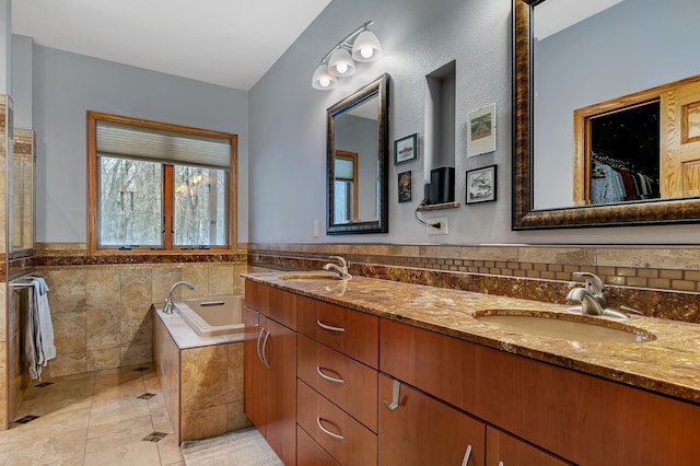 bathroom featuring tile patterned flooring, a relaxing tiled tub, and vanity