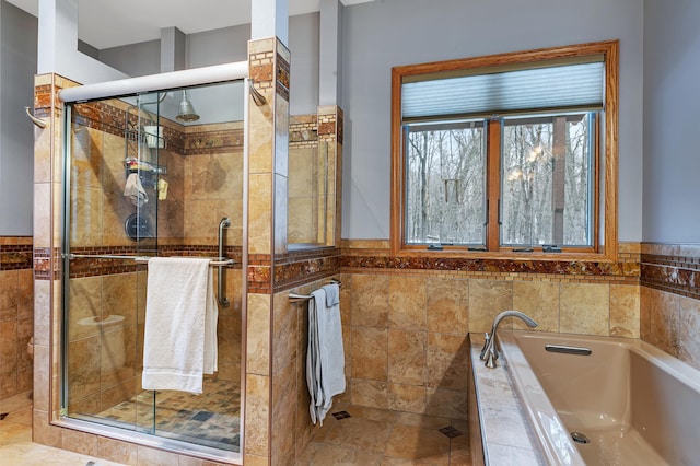 bathroom with tile walls, separate shower and tub, and tile patterned floors