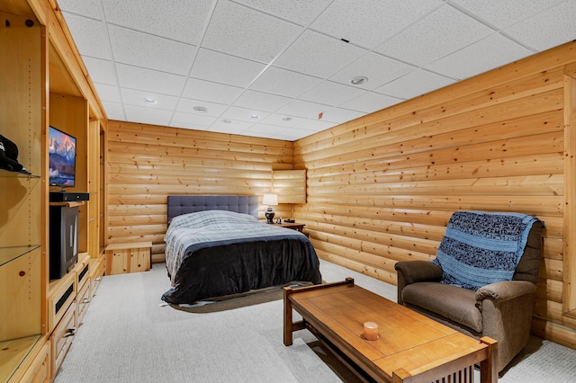 carpeted bedroom with log walls and a drop ceiling