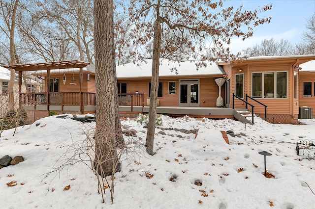 snow covered rear of property with central AC unit and a deck