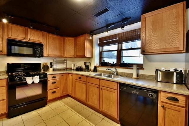 kitchen featuring black appliances, light tile patterned floors, and sink