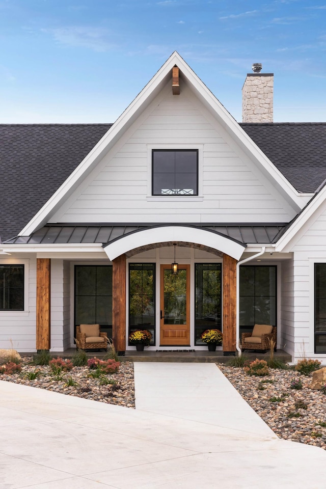 935 Lakewood Hills Rd, Eagan, MN 55123 - view of exterior entry with a shingled roof, a standing seam roof, a chimney, and metal roof