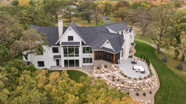 935 Lakewood Hills Rd, Eagan, MN 55123 - rear view of property with a sunroom, a patio area, a shingled roof, a chimney, and a lawn