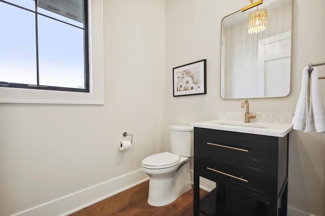 935 Lakewood Hills Rd, Eagan, MN 55123 - half bathroom featuring baseboards, toilet, wood finished floors, and vanity