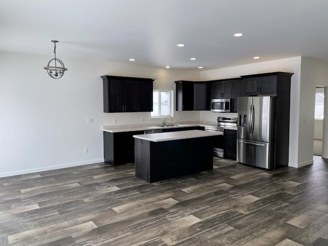 kitchen featuring appliances with stainless steel finishes, sink, dark wood-type flooring, pendant lighting, and a kitchen island