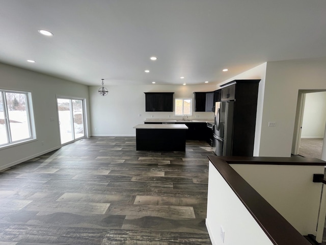 kitchen with dark hardwood / wood-style floors, stainless steel fridge, decorative light fixtures, a center island, and sink