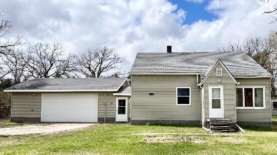 rear view of property featuring a garage and a yard