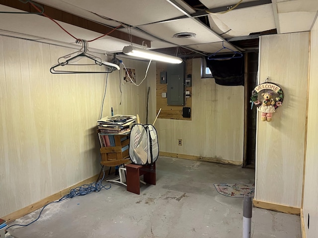 basement featuring wood walls and electric panel