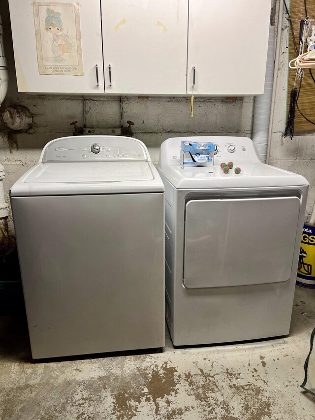 clothes washing area featuring cabinets and washer and clothes dryer