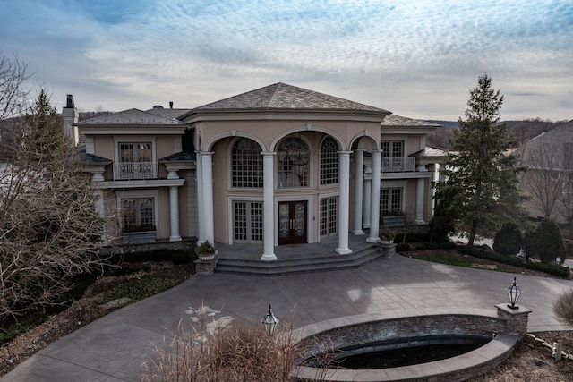 view of front of property featuring a balcony, a patio area, and french doors