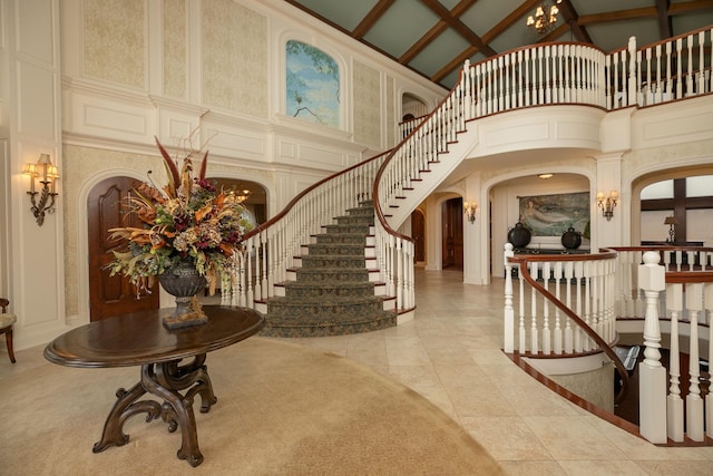 tiled foyer entrance featuring a notable chandelier and high vaulted ceiling