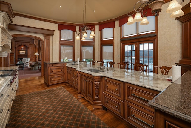 kitchen featuring an inviting chandelier, dark stone counters, hanging light fixtures, and sink