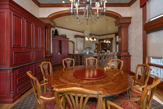 dining area with an inviting chandelier, decorative columns, ornamental molding, and dark wood-type flooring