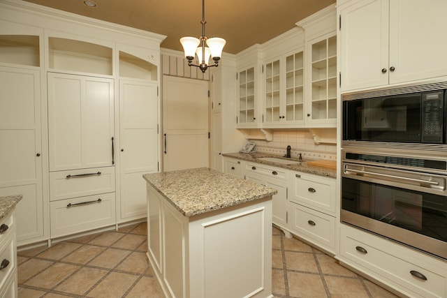 kitchen featuring a chandelier, black microwave, backsplash, hanging light fixtures, and oven