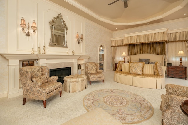 carpeted bedroom with ornamental molding, a tiled fireplace, and a raised ceiling