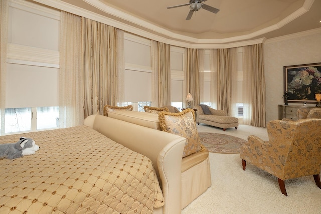 bedroom with ceiling fan, crown molding, a tray ceiling, and light colored carpet