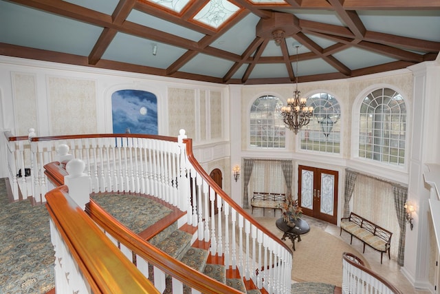 staircase with coffered ceiling, a chandelier, and carpet