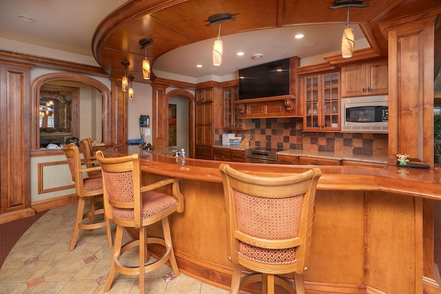 bar with backsplash, hanging light fixtures, stainless steel microwave, and range