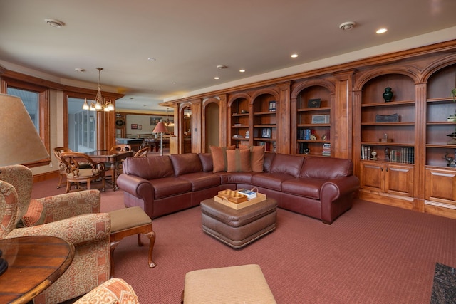 living room featuring built in shelves, carpet flooring, and a notable chandelier