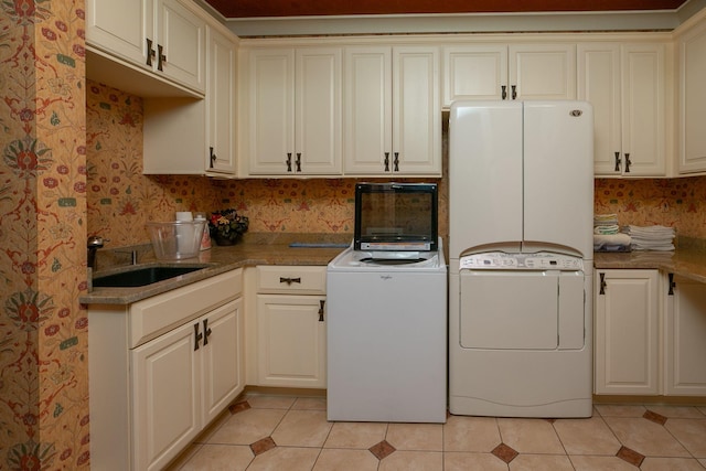 laundry room with sink, cabinets, washer and dryer, and light tile floors