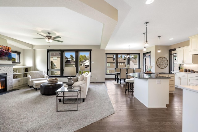 living room with dark wood-type flooring, ceiling fan with notable chandelier, and sink