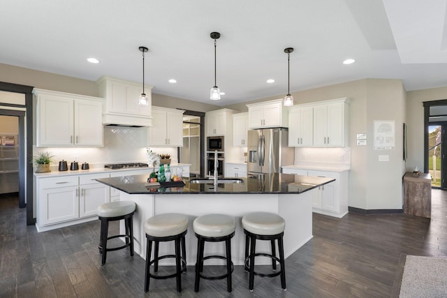 kitchen featuring an island with sink, hanging light fixtures, and appliances with stainless steel finishes