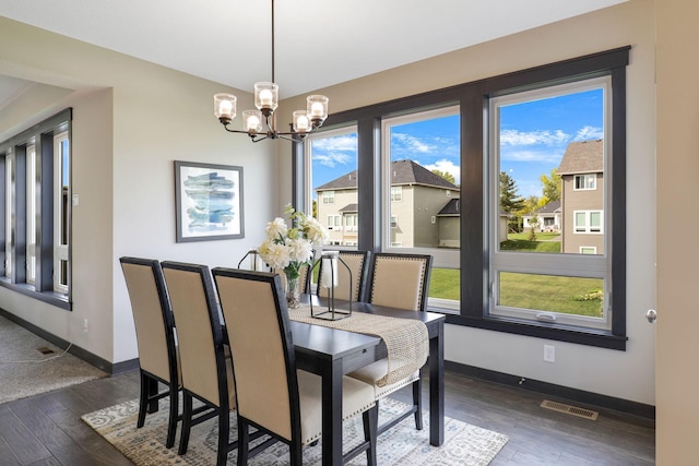 dining room with an inviting chandelier, dark wood-type flooring, and a healthy amount of sunlight