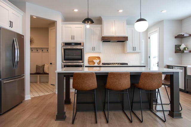 kitchen featuring white cabinetry, appliances with stainless steel finishes, tasteful backsplash, decorative light fixtures, and light wood-type flooring