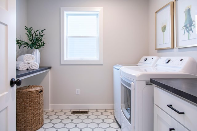 washroom featuring plenty of natural light, washing machine and clothes dryer, and cabinets