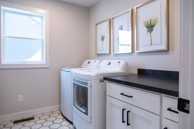 clothes washing area with washer and clothes dryer and cabinets