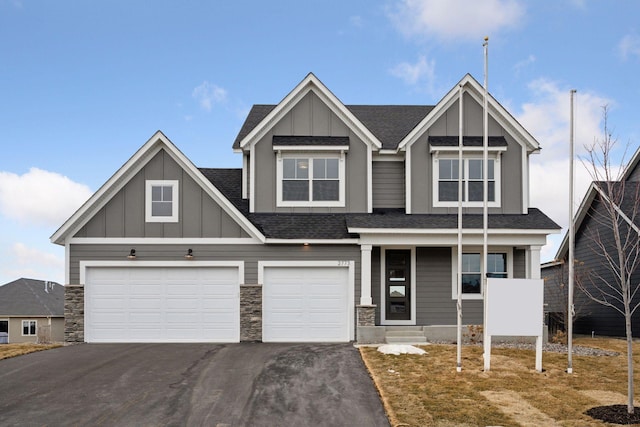 craftsman inspired home with a garage, a shingled roof, aphalt driveway, and board and batten siding