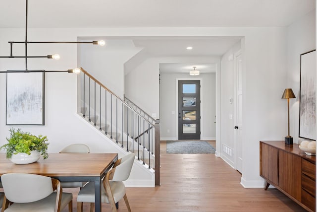 foyer entrance with light wood-type flooring, baseboards, and stairway