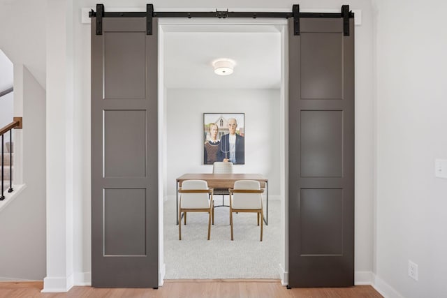 office area featuring baseboards, a barn door, and light wood-style floors