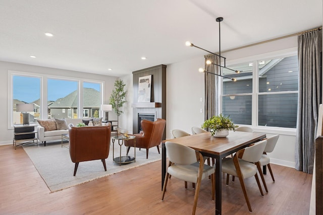 dining room with a large fireplace, recessed lighting, light wood-style flooring, and a notable chandelier