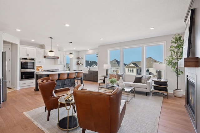 living area with light wood-type flooring, a fireplace, baseboards, and recessed lighting