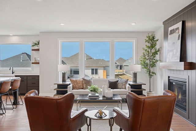 living room with light wood-type flooring, a large fireplace, a textured ceiling, and recessed lighting