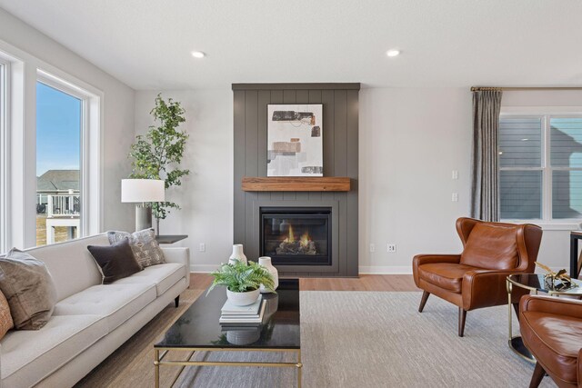 living area featuring recessed lighting, a fireplace, wood finished floors, and baseboards