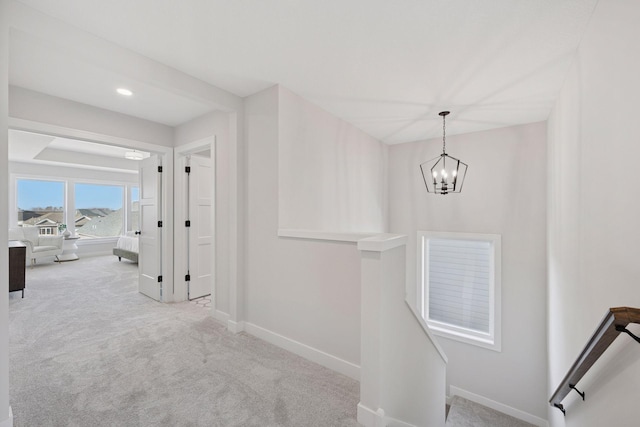 hallway featuring carpet, baseboards, and an upstairs landing