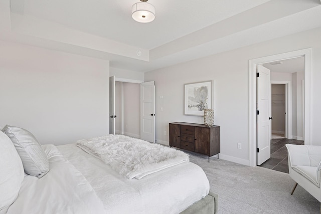 bedroom with carpet floors, a raised ceiling, and baseboards