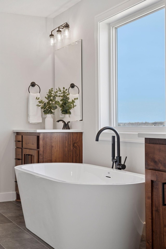 full bathroom with a soaking tub, vanity, and baseboards