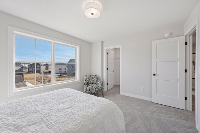 bedroom with carpet, baseboards, and a walk in closet